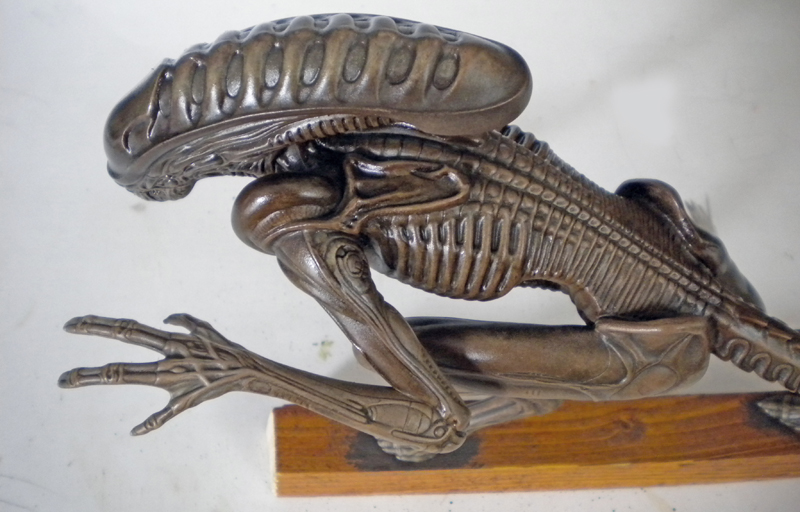 Maquette de la créature Alien 3 peinte en brun métallisé, posée sur socle bois