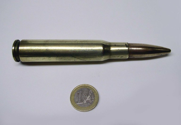 Cartouche réelle de calibre 50 Browning posée près d'une pièce d'un euro pour l'échelle