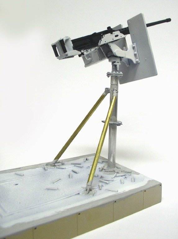 Mitrailleuse Browning M2 en apprêt gris sur affût trépied, socle jonché de douilles