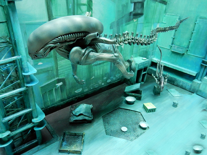 Maquette d'un alien aquatique nageant dans un décor industriel sous-marin aux tons verts
