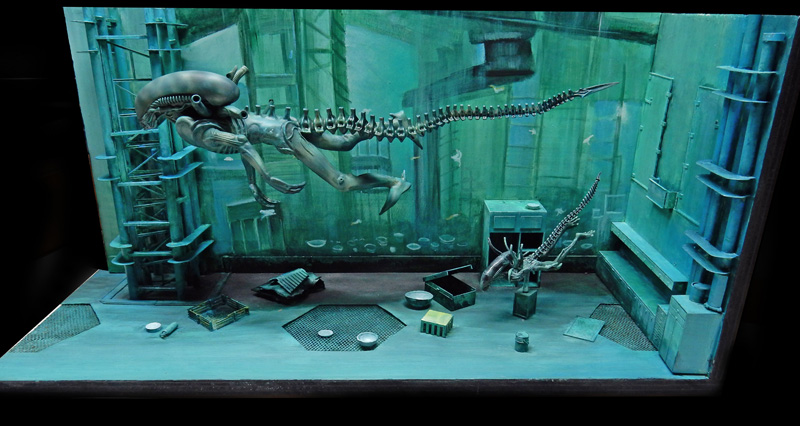 Diorama sous-marin aux teintes vertes avec deux créatures Aqualien nageant dans une station immergée