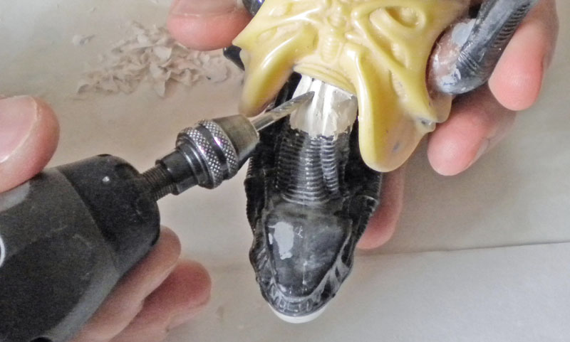 Ponçage à la mini-perceuse de la tête en résine de la maquette Aqualien tenue à la main
