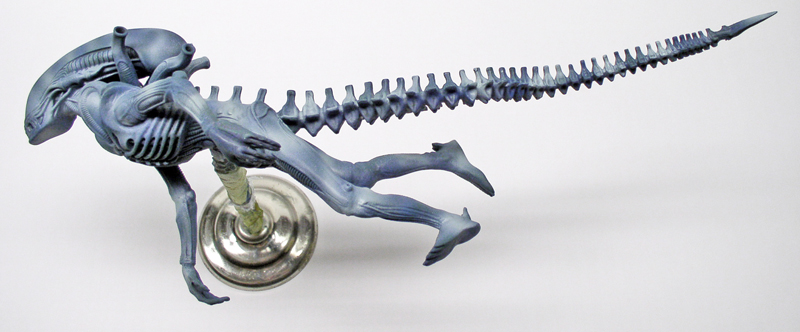 Maquette d'alien quadrupède bleu-gris à longue queue segmentée, montée sur socle métallique
