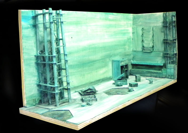 Diorama de maquette aux teintes vertes représentant une salle industrielle sous-marine avec structures et caisses