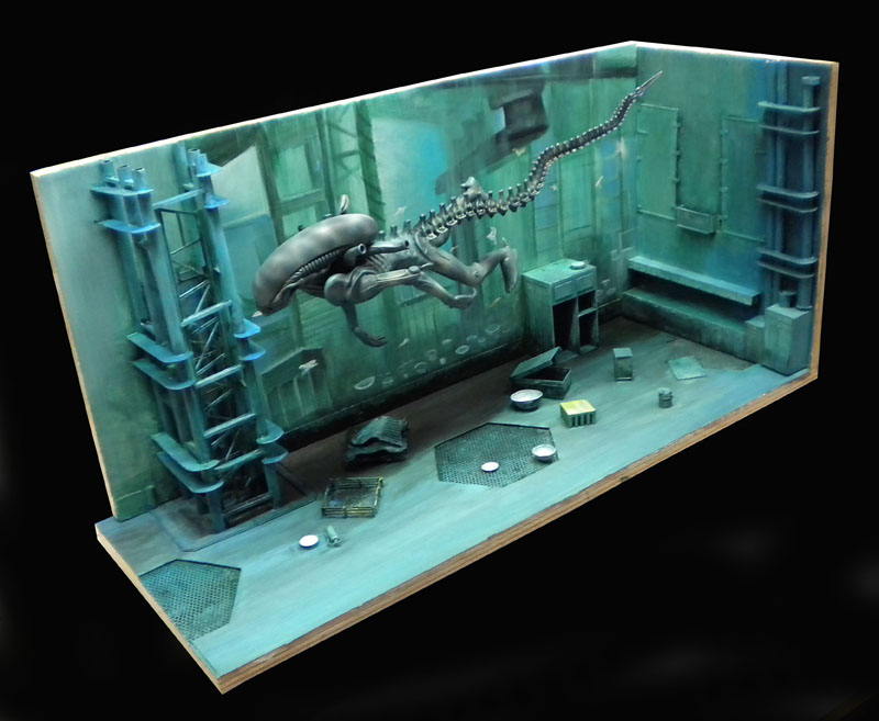 Diorama de maquette montrant un Alien xénomorphe dans un décor industriel verdâtre aux parois métalliques