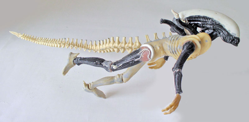 Maquette d'Aqualien hybride alien et dinosaure avec longue queue squelettique sur fond clair