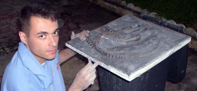 Maquettiste présentant un bas-relief gris sculpté représentant l'Alien, le Huitième Passager