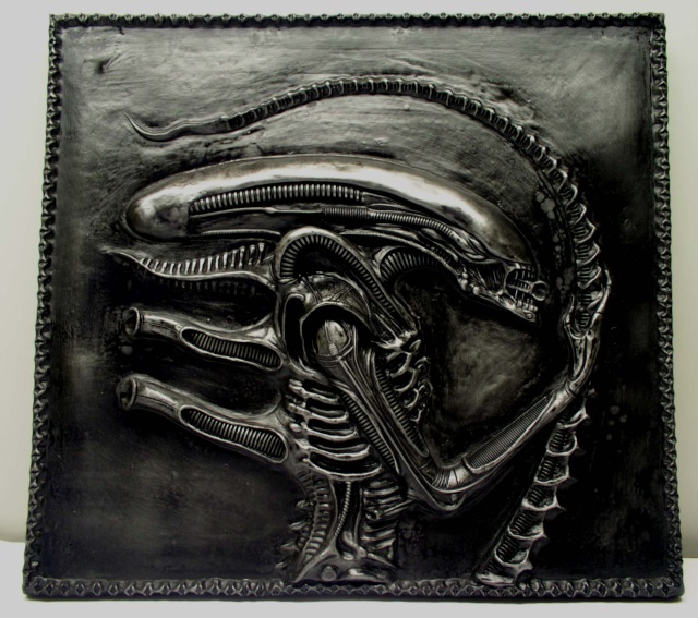 Bas relief patiné en noir métallique représentant la créature Alien sur plaque carrée