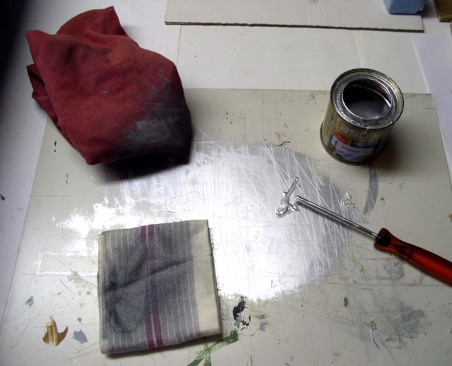Pot de peinture métallique, chiffons et pinceau sur plan de travail pour préparer la patine