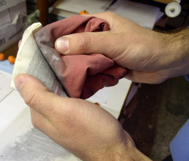 Mains préparant un chiffon imprégné de pigments pour appliquer la patine du bas-relief