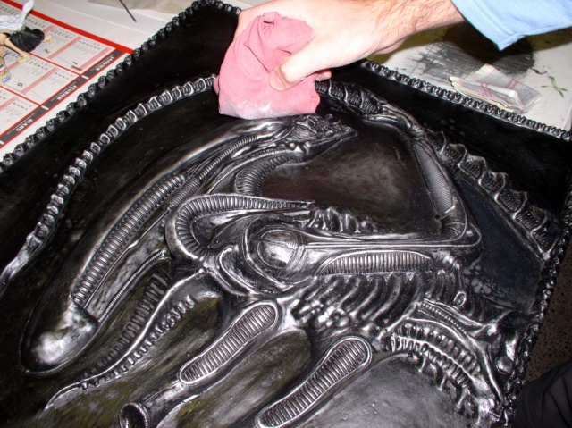 Application au chiffon rose d'une patine argentée sur le bas-relief Alien noir
