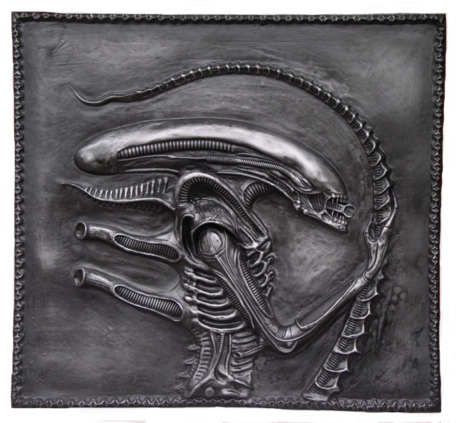 Bas-relief patiné métallique représentant la tête et la queue de l'Alien sur fond sombre