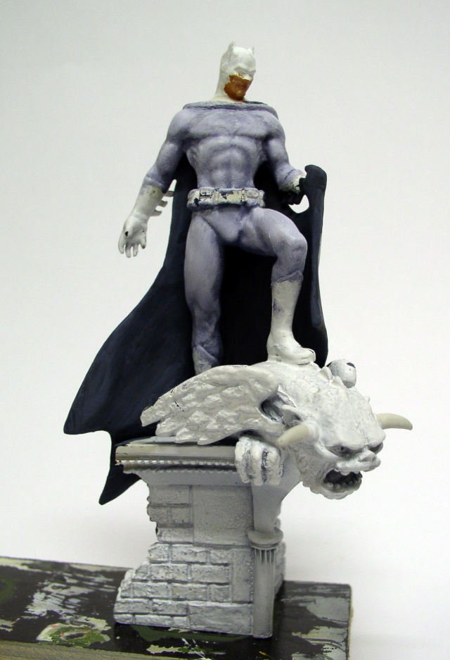 Figurine Batman en cours de peinture posée sur une gargouille en pierre