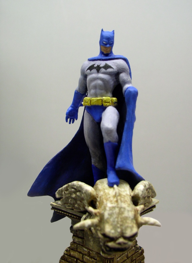 Figurine peinte de Batman en costume gris et bleu debout sur une gargouille