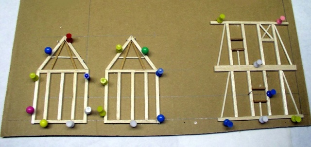 Ossatures en colombage de bois assemblées et maintenues par des épingles colorées sur carton