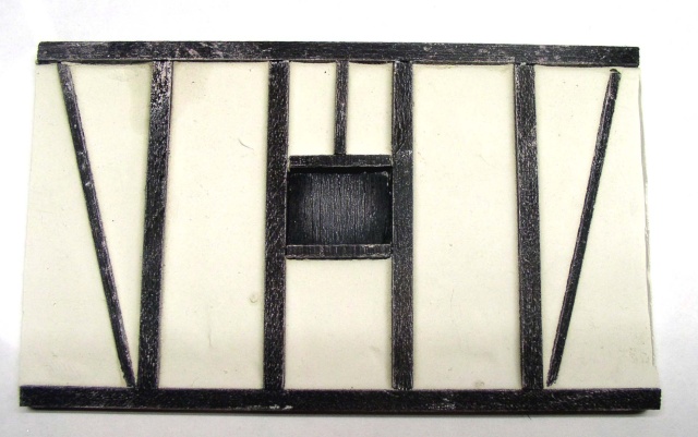 Mur de maquette à colombage peint blanc et noir avec petite fenêtre carrée centrale