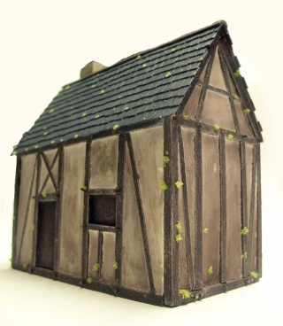 Maquette de grange médiévale à colombage avec toit d'ardoises mousseux sur fond blanc