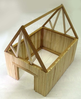 Maquette en bois d'une grange médiévale avec charpente de toit triangulaire en cours de construction