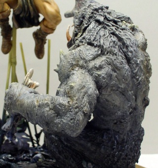 Figurine de créature monstrueuse grise face à Conan armé sur un diorama de maquettisme