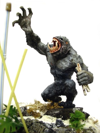 Figurine peinte de créature simiesque rugissante brandissant un bras sur un diorama rocheux