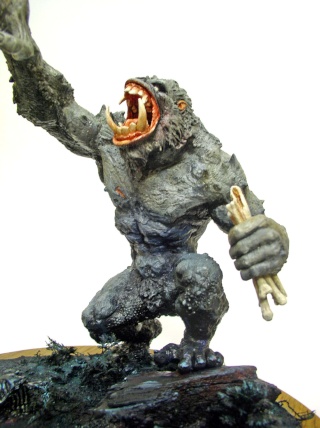 Figurine de créature monstrueuse grise gueule ouverte tenant un personnage humain dans sa main