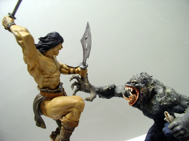 Figurine peinte de Conan brandissant épée et dague face à une créature simiesque rugissante