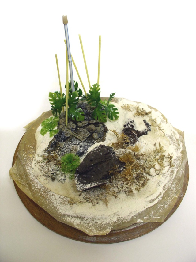Diorama de maquette en cours sur socle rond avec sable, rochers, végétation tropicale et masquage adhésif