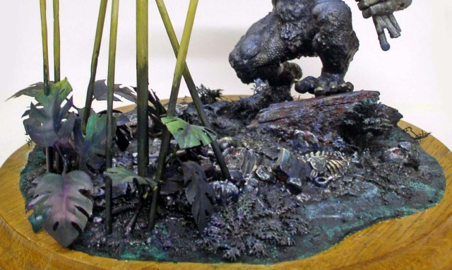 Diorama de maquette avec créature monstrueuse, végétation tropicale et squelette sur socle en bois