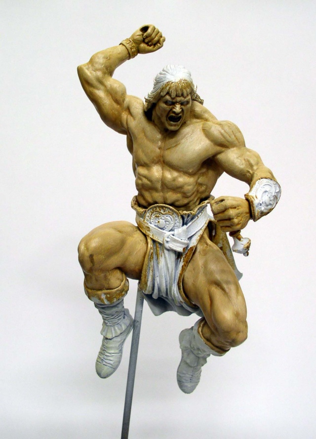 Figurine peinte d'un guerrier musclé bondissant, poing levé, en pagne blanc doré