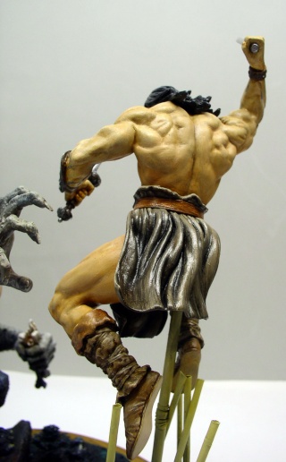 Figurine de Conan musclé vu de dos brandissant une dague face à des créatures