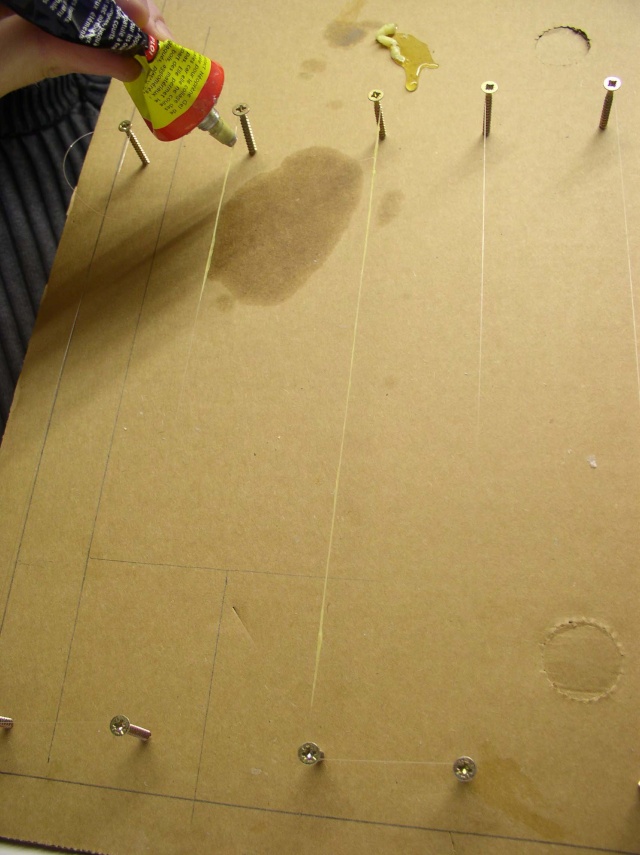 Application de colle sur un support en carton avec vis pour fixer la figurine