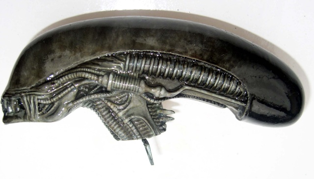 Tête de figurine Alien peinte en gris métallisé montrant le crâne allongé et le cou nervuré
