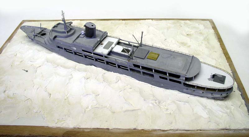 Maquette de navire gris sur diorama de mer blanche dans un cadre en bois