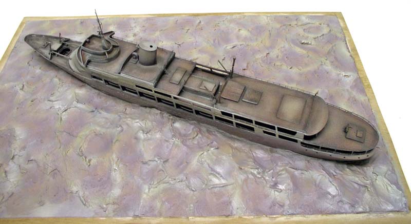 Maquette de navire fantôme gris sur diorama représentant une mer mauve texturée