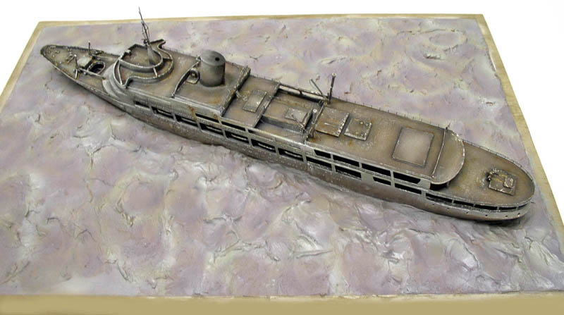 Maquette de navire fantôme vieilli posée sur un diorama imitant la surface de l'eau