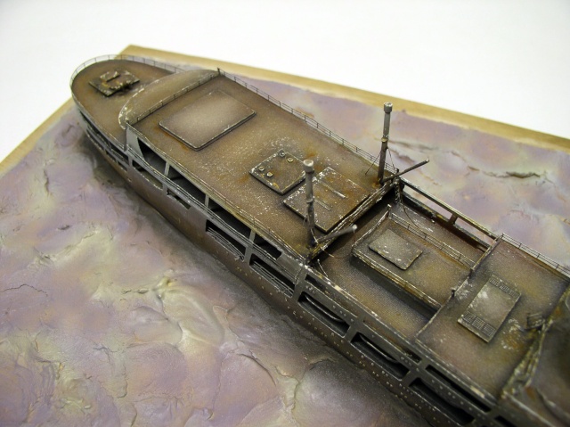 Maquette de navire fantôme rouillé et abandonné posée sur un diorama de mer violacée