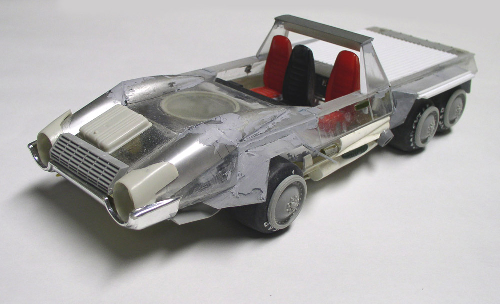 Maquette de véhicule futuriste à six roues avec sièges rouges, carrosserie argentée en cours de mastiquage