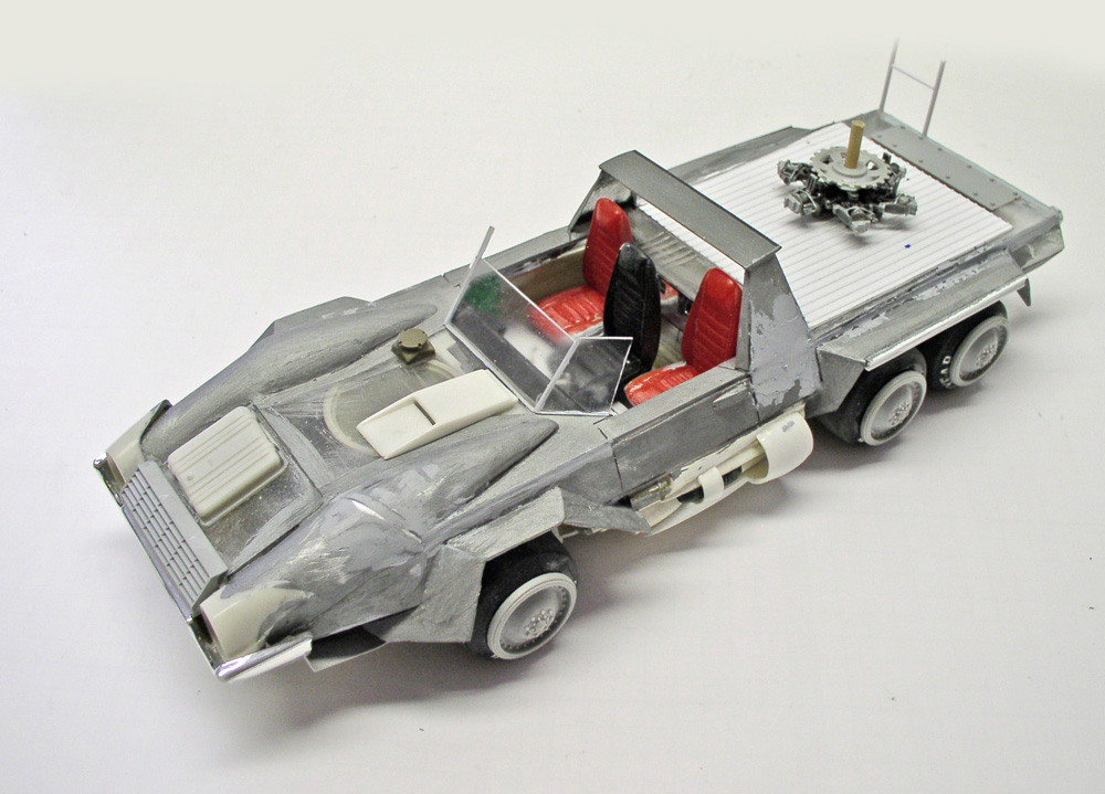 Maquette de véhicule militaire futuriste argenté à six roues avec sièges rouges et tourelle