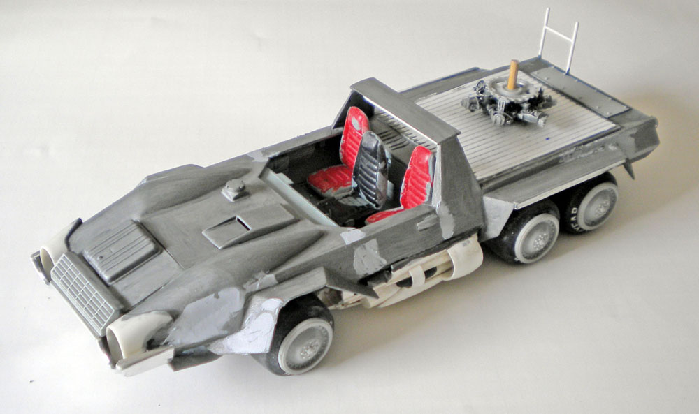 Maquette de véhicule militaire gris à six roues avec sièges rouges et plateforme arrière