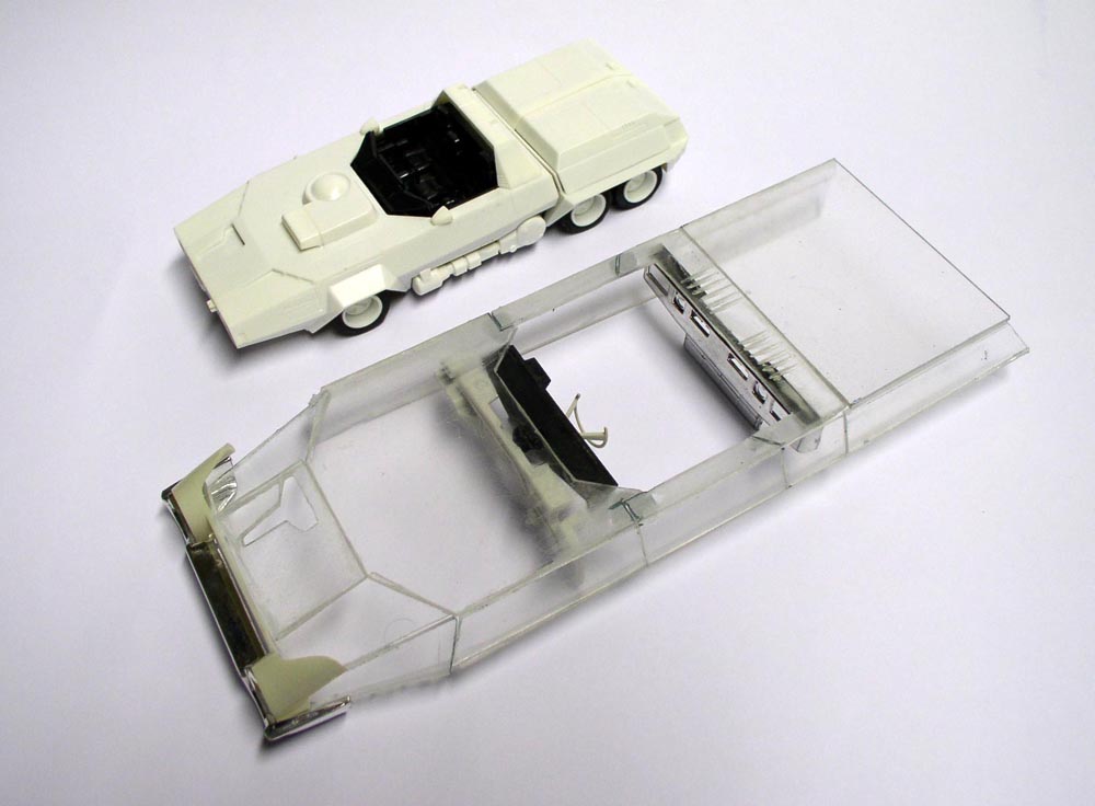 Maquette de véhicule futuriste blanc à côté de sa carrosserie transparente sur fond clair