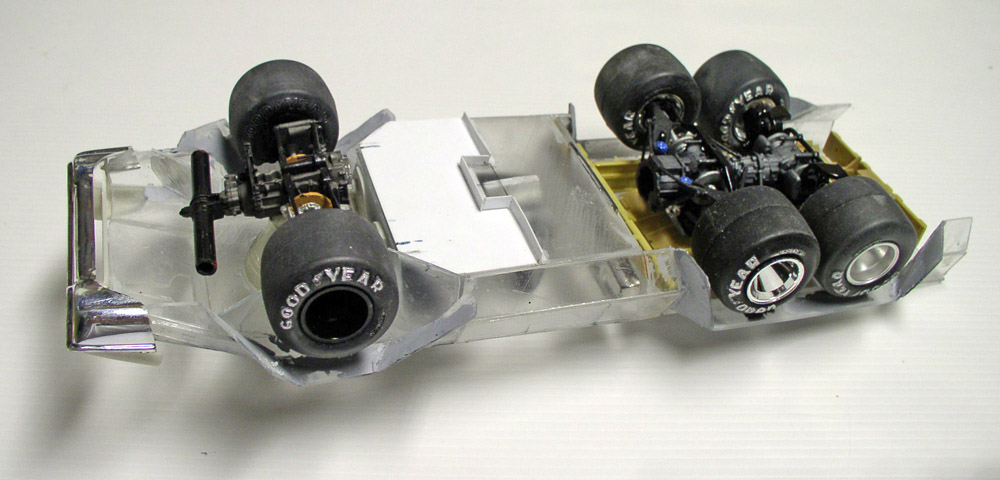 Dessous d'une maquette de véhicule à six roues Goodyear montrant châssis transparent et trains roulants détaillés