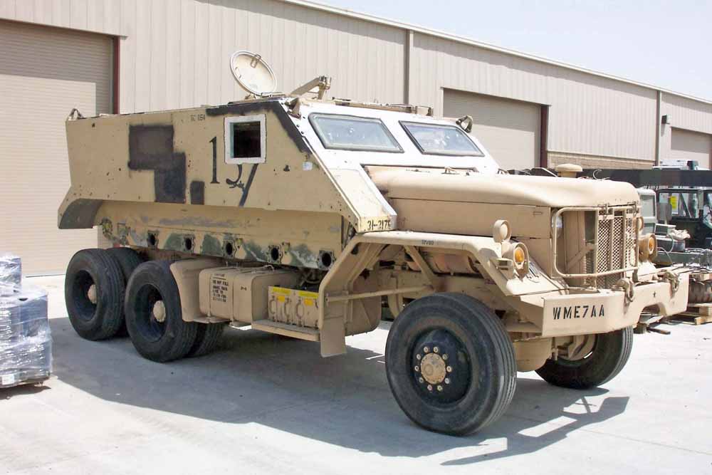 Camion militaire blindé sable Guntruck américain stationné devant un hangar en Irak