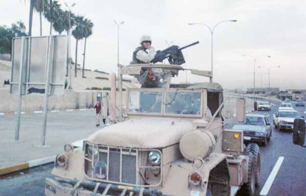 Camion militaire blindé avec mitrailleuse et soldat américain sur autoroute irakienne en 2003