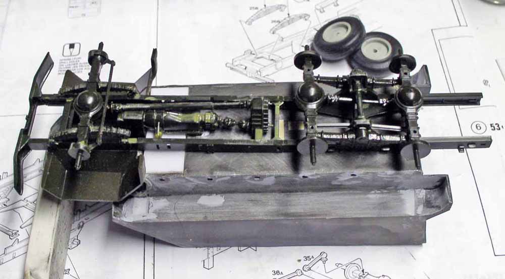 Châssis de maquette de camion avec essieux et transmission peints, posé sur la notice de montage