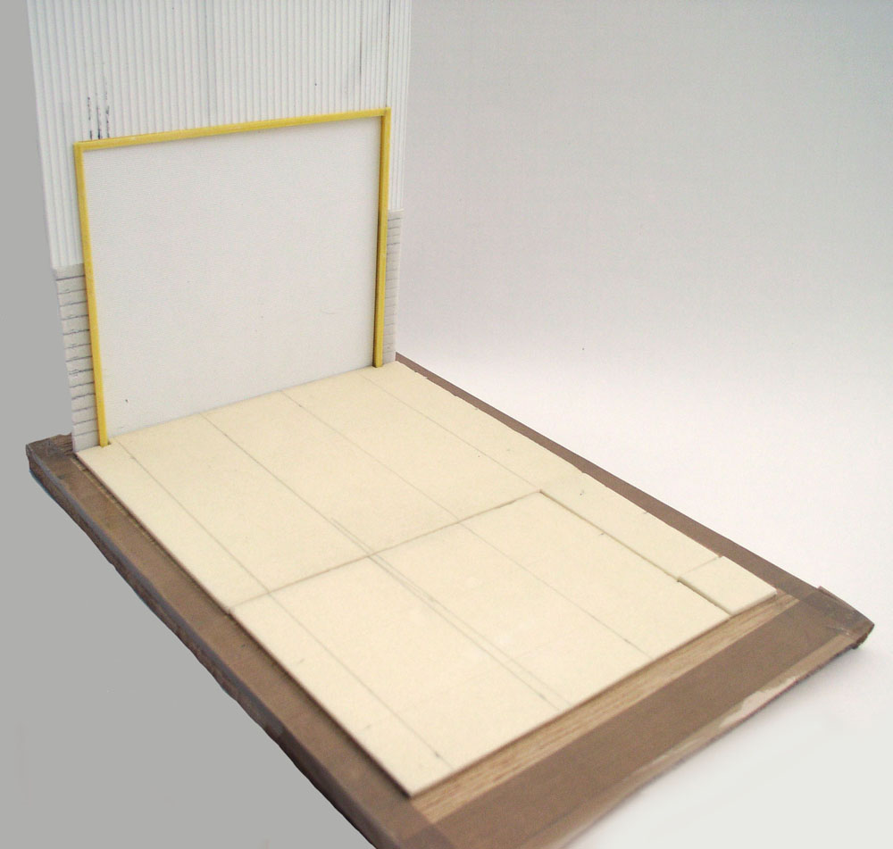Base de diorama en construction avec sol carrelé et mur clair encadrant une ouverture jaune