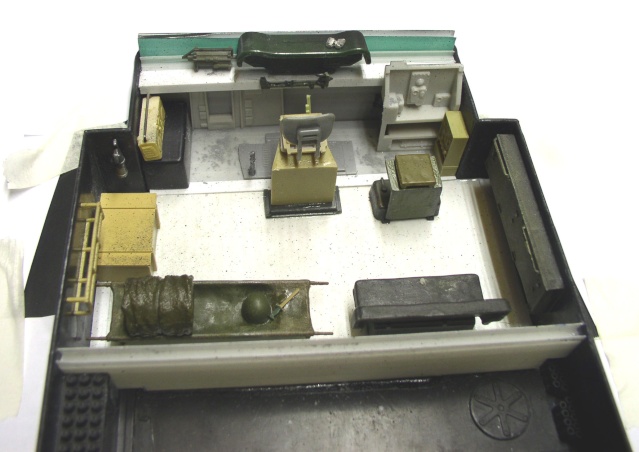 Détail intérieur de la maquette d'hovercraft avec poste de pilotage, sièges et équipements militaires peints en kaki