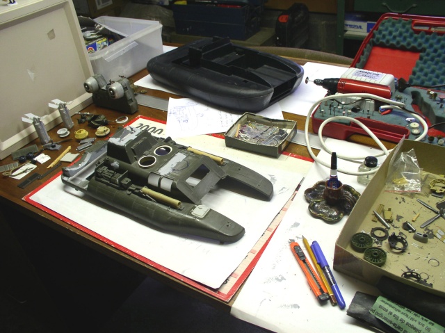 Maquette d'hovercraft en construction sur l'établi avec outils, peintures et pièces détachées