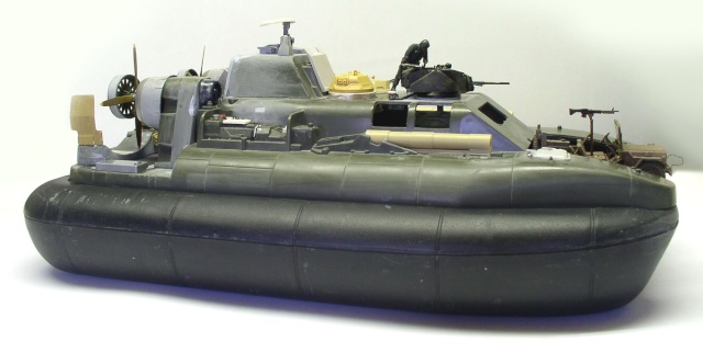 Maquette d'hovercraft militaire vert avec hélice, mitrailleuses et figurine, vue de profil