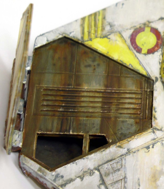 Trappe ouverte rouillée sur fuselage patiné de maquette d'épave de vaisseau spatial avec marquages jaunes et rouges