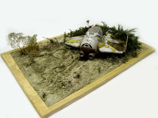 Diorama d'épave de vaisseau spatial échoué dans un sol boueux envahi par la végétation
